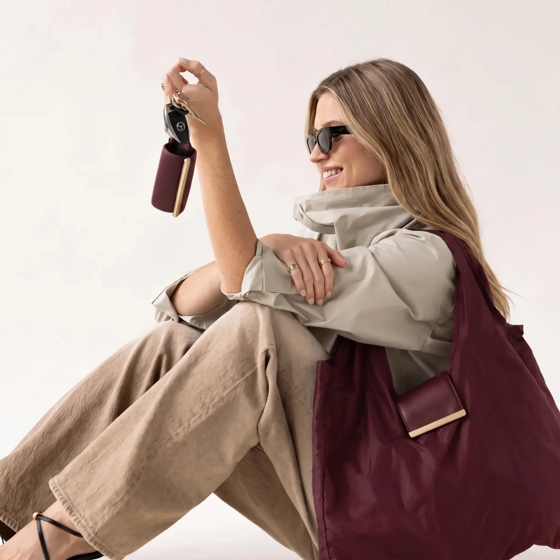Model with the burgundy cliqué tote on her shoulder holding keys with the pouch clipped on